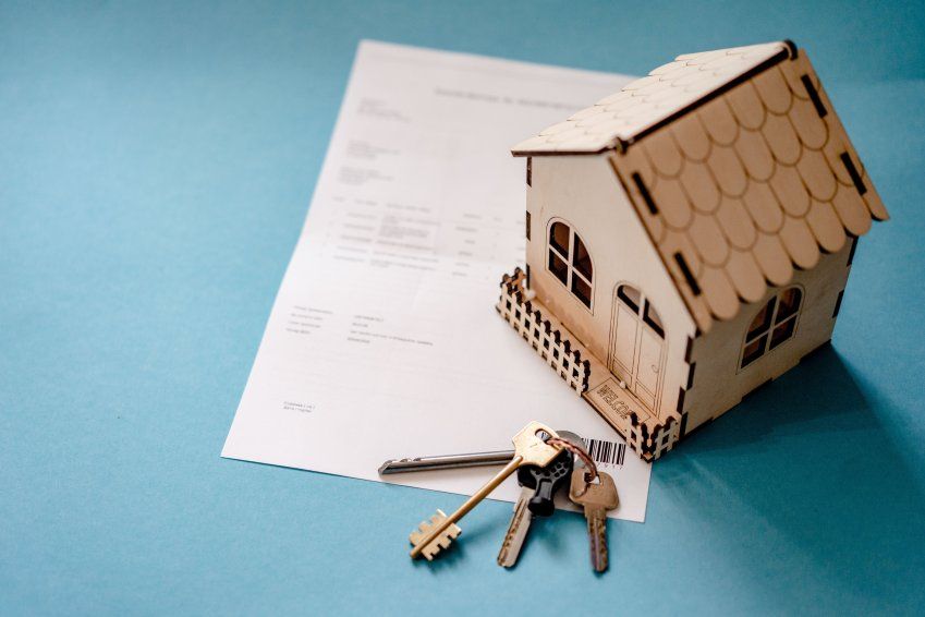 Maqueta de una vivienda colocada sobre documentación hipotecaria con varias llaves, imagen relacionada con reclamaciones de gastos hipotecarios en Burgos