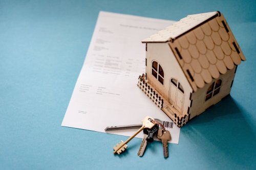 Maqueta de una vivienda colocada sobre documentación hipotecaria con varias llaves, imagen relacionada con reclamaciones de gastos hipotecarios en Burgos